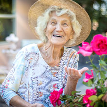 Elderly woman suffering from Alzheimer's cutting flowers in her garden. 