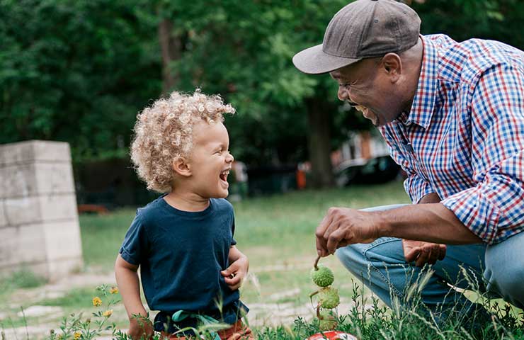 grandfather playing in the grass with his grandson